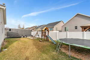 View of yard featuring a residential view, a trampoline, a playground, and a fenced backyard