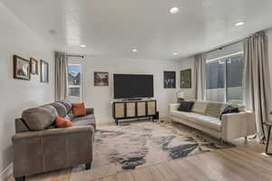 Living area with baseboards, recessed lighting, wood finished floors, and a textured ceiling