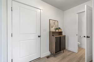 Hallway featuring visible vents, baseboards, and light wood finished floors