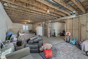 Below grade area featuring freestanding refrigerator and gas water heater