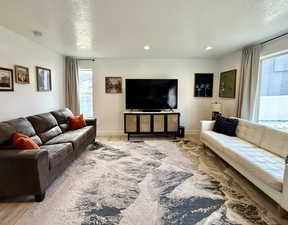 Living room with recessed lighting, baseboards, a healthy amount of sunlight, and wood finished floors