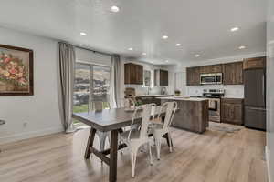 Dining space with baseboards, light wood-type flooring, recessed lighting, and a textured ceiling