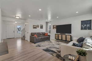 Living area with light wood-style flooring, stairway, recessed lighting, and a healthy amount of sunlight