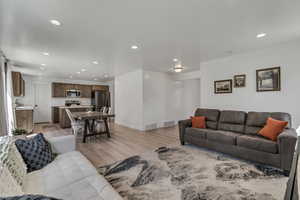 Living area with light wood-type flooring, visible vents, and recessed lighting