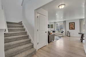 Stairs featuring a textured ceiling, wood finished floors, baseboards, and recessed lighting