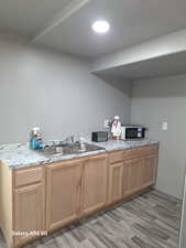 Kitchen with a sink, light stone countertops, and light wood finished floors