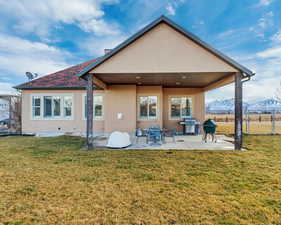Back of property featuring a yard, stucco siding, fence, and a patio area