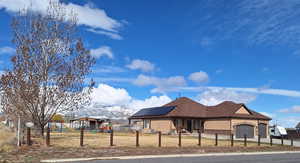 View of front of house featuring a garage, playground community, a fenced front yard, and solar panels