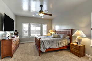 Bedroom featuring light carpet, baseboards, and ceiling fan
