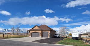 View of front facade with concrete driveway, a mountain view, fence, and an attached garage