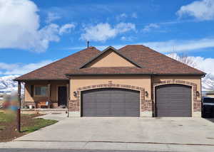 View of front of house featuring a shingled roof, an attached garage, a mountain view, and concrete driveway