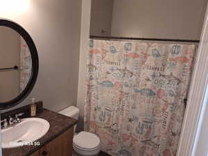 Bathroom with toilet, vanity, and a shower with curtain