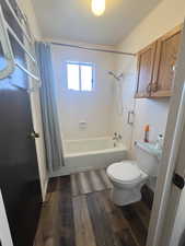 Bathroom featuring toilet, LVP wood finished floors, and shower / tub combo with curtain