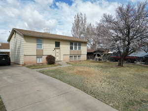 View of front of property with brick, siding, fence, a front lawn, and concrete driveway