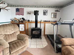 Living area with light colored carpet, a textured ceiling, a gas stove, and light tile patterned floors
