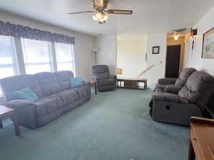 Living room with visible vents, carpet, ceiling fan, and a textured ceiling