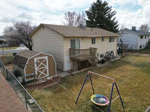 Rear view of property with an outbuilding, a shed, roof with shingles, and fence