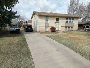 Split entry home with a front yard, fence, and concrete driveway