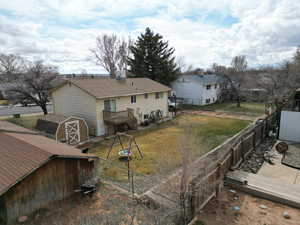 Rear view of house featuring, roof with shingles, a lawn, a fenced backyard, and a storage shed