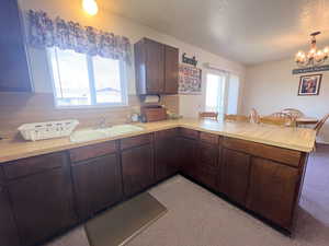 Kitchen with light countertops, a sink, a peninsula, and a wealth of natural light