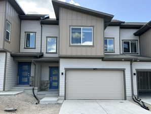 View of property featuring concrete driveway, an attached garage, and board and batten siding