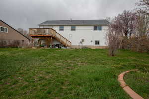 Back of property with a lawn, stairs, fence, and a wooden deck