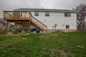 Rear view of property with a wooden deck, fence, stairway, and a yard
