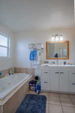 Bathroom with a tub with jets, tile patterned flooring, and vanity