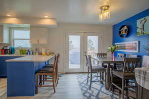Dining space with light wood finished floors, a wealth of natural light, french doors, and a textured ceiling