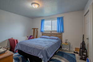 Bedroom with baseboards, a textured ceiling, and light wood finished floors