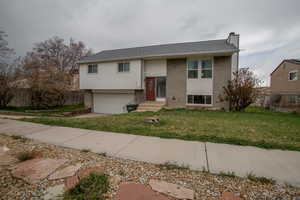 Split foyer home with a chimney, fence, and brick siding