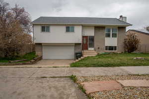 Split foyer home featuring fence, driveway, an attached garage, and brick siding