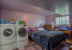 Tiled bedroom with visible vents, washing machine and clothes dryer, and a textured ceiling