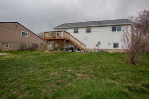 Rear view of property with stairway, a deck, and a lawn