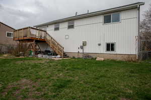 Rear view of property with stairs, a wooden deck, fence, and a yard