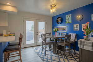 Dining room with baseboards, a textured ceiling, french doors, and light wood-type flooring