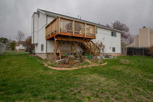 Back of house with a deck, fence, and a yard