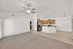 Kitchen with visible vents, open floor plan, a ceiling fan, vaulted ceiling, and stainless steel appliances