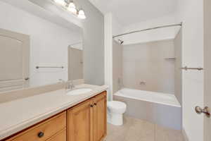 Bathroom featuring tile patterned floors, toilet, vanity, and shower / washtub combination