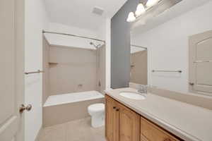 Bathroom featuring bathtub / shower combination, vanity, visible vents, toilet, and tile patterned floors