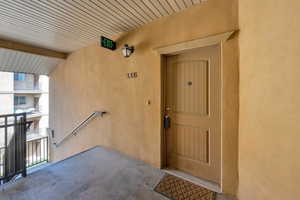 View of exterior entry with a balcony and stucco siding