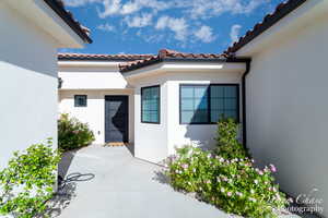 View of exterior entry featuring stucco siding, a tiled roof, and a patio area