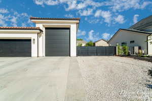 Garage with a gate, fence, and concrete driveway