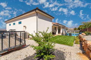 View of side of property featuring a patio area, a fenced backyard, stucco siding, and a tiled roof