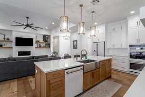 Two tone kitchen with open floor plan, two tone cabinets, pendant lighting, white appliances, and dark wood-style flooring