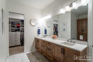 Full bath featuring marble finish floor, double vanity, a sink, and a walk in closet