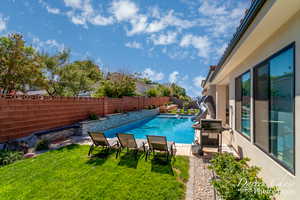 View of pool with area for grilling, a water slide, a fenced in pool, a fenced backyard, and a lawn