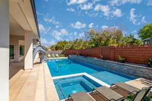 Integrated pool / hot tub featuring a water slide, a patio, and a fenced backyard