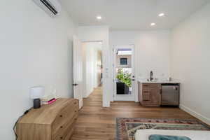 Bar with recessed lighting, light wood-type flooring, stainless steel dishwasher, light stone countertops, and wood finish cabinetry