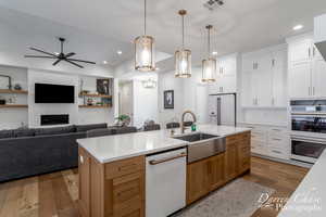 Kitchen with a sink, wood finished floors, open floor plan, white appliances, and visible vents